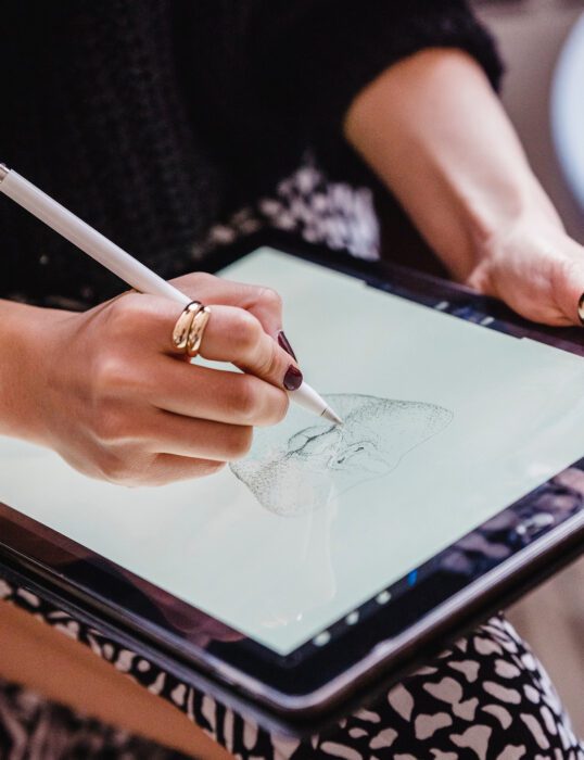 Woman's hand drawing a man's face on an iPad
