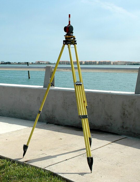 Surveying equipment on tripod overlooking water